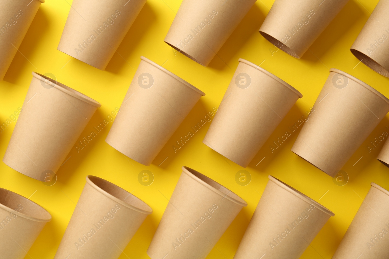 Photo of Paper cups on yellow background, flat lay. Eco friendly lifestyle