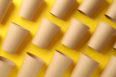 Photo of Paper cups on yellow background, flat lay. Eco friendly lifestyle