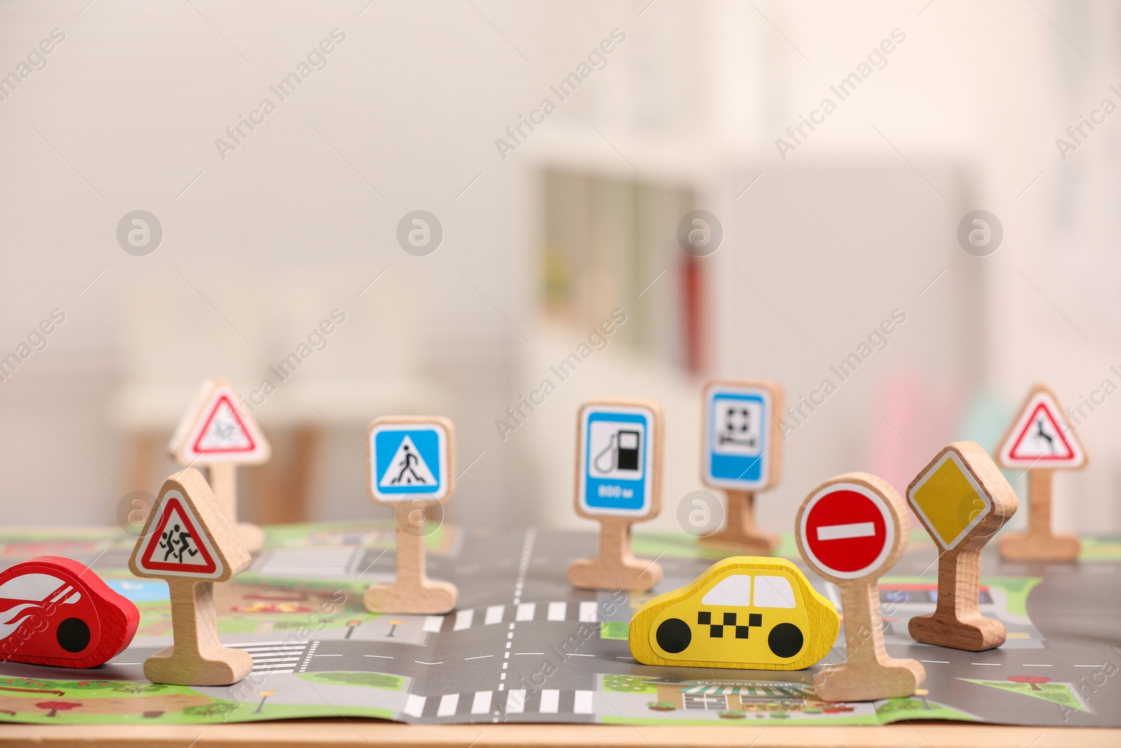 Photo of Set of wooden road signs and cars on table indoors, closeup. Children's toys