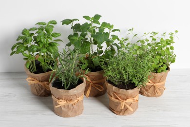 Photo of Different aromatic potted herbs on white wooden table