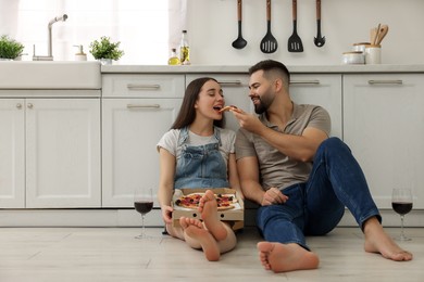 Photo of Happy young couple eating pizza in kitchen. Space for text