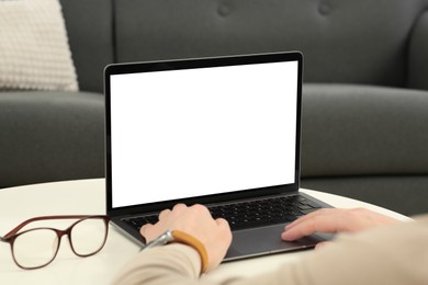 Man working with laptop at white table indoors, closeup