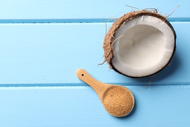 Photo of Spoon with coconut sugar and half of fruit on light blue wooden table, top view. Space for text