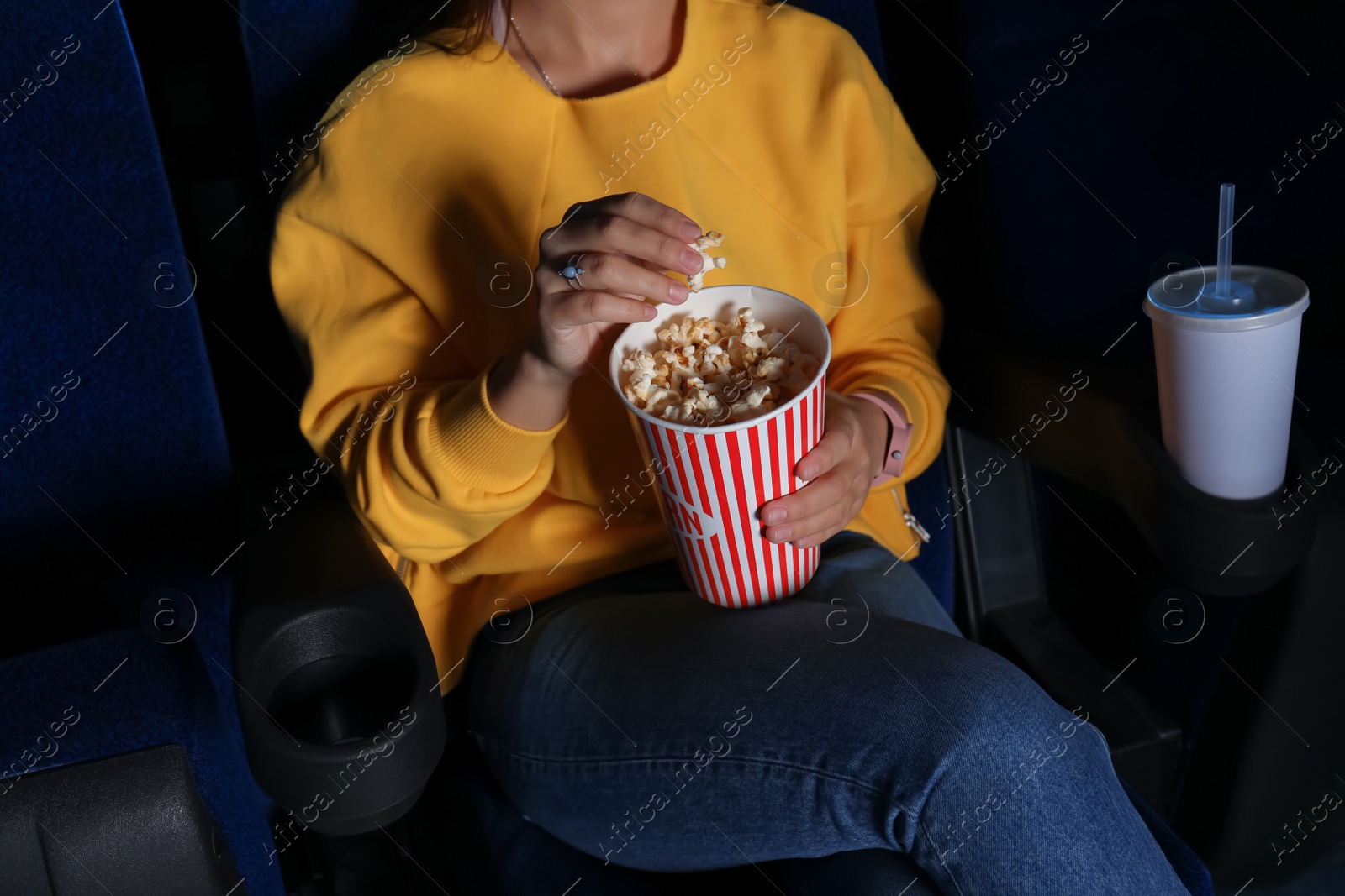 Photo of Young woman with popcorn watching movie in cinema, closeup