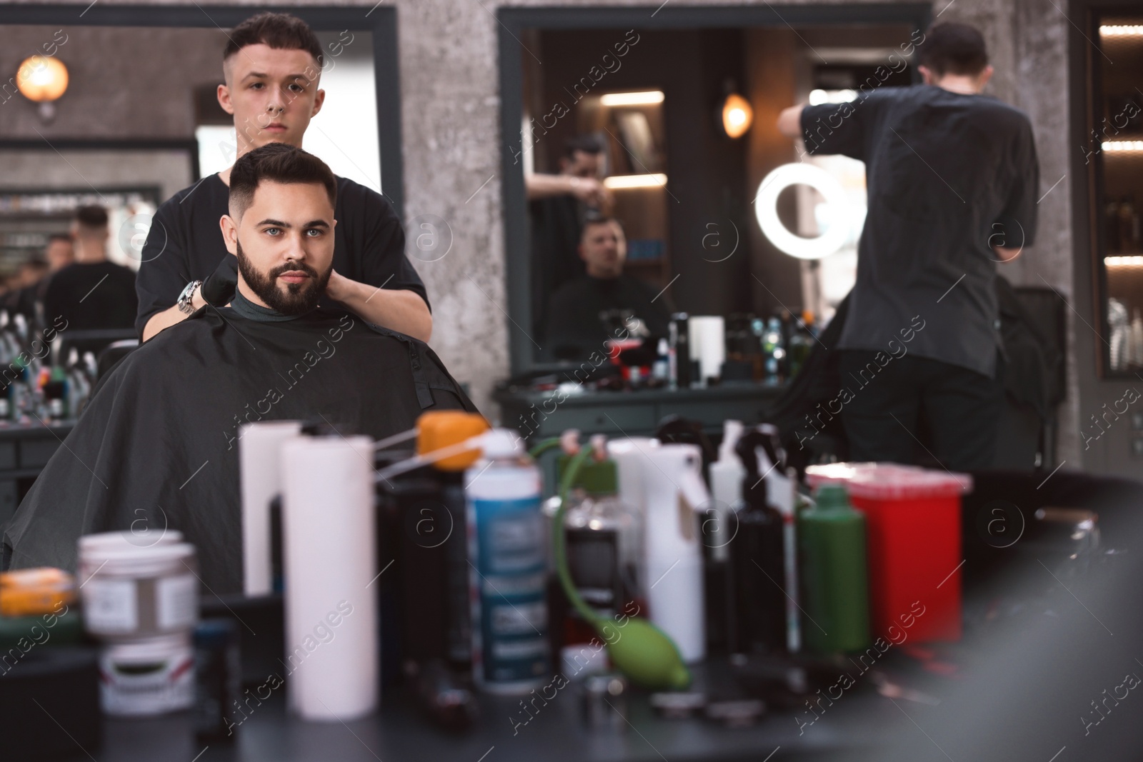 Photo of Professional hairdresser working with client in barbershop