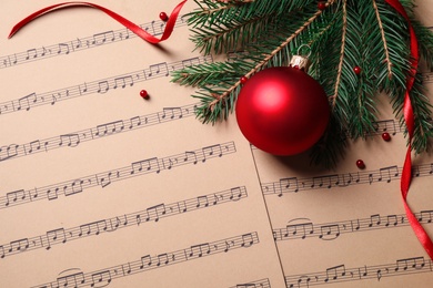 Photo of Flat lay composition with Christmas decorations on music sheets, space for text