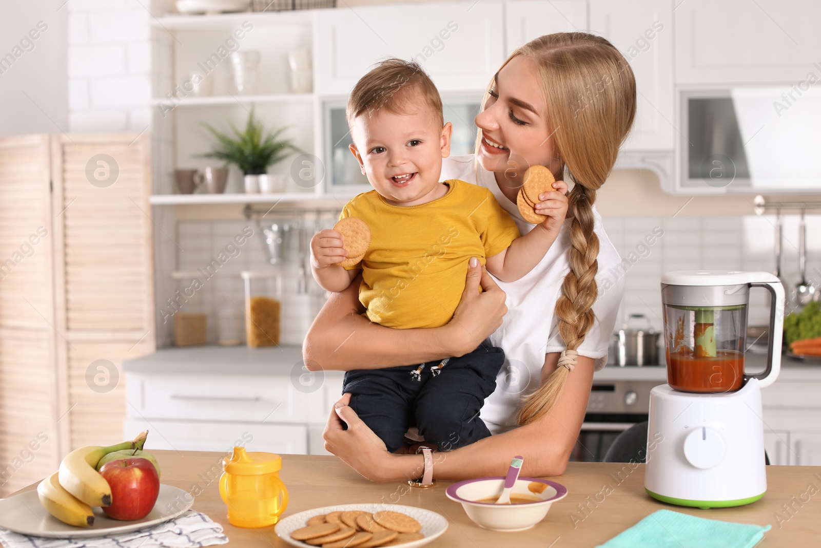 Photo of Woman feeding her child in kitchen. Healthy baby food