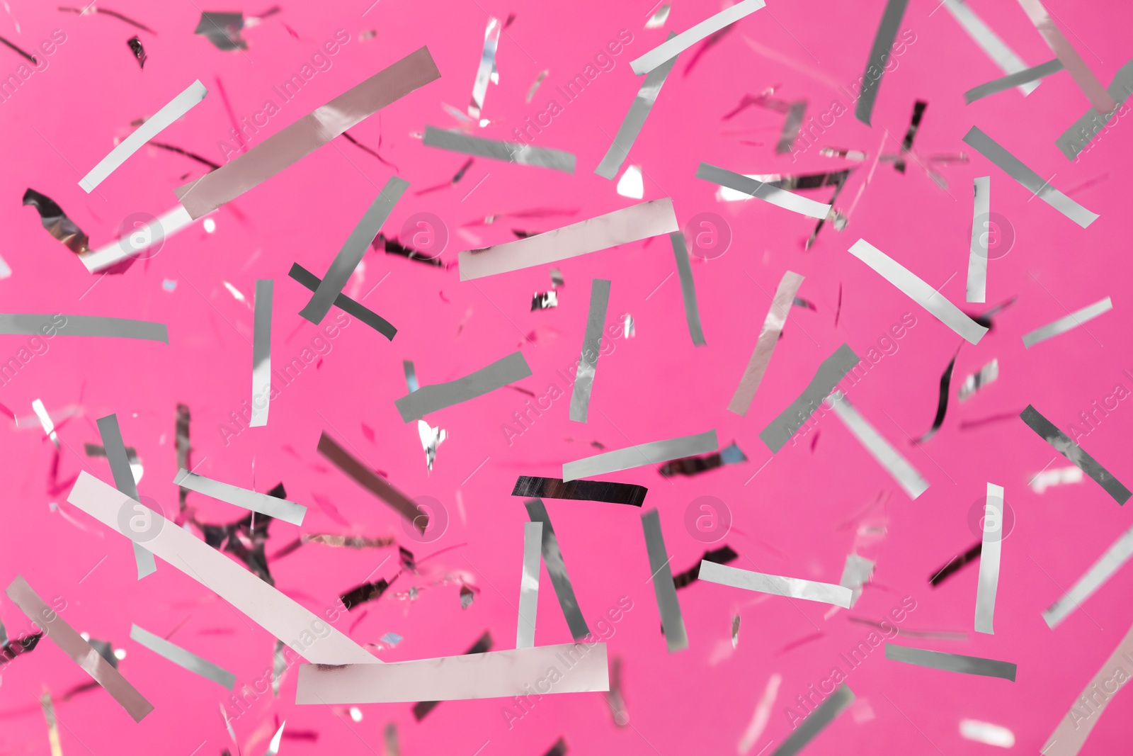 Image of Shiny silver confetti falling down on pink background