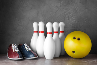 Photo of Bowling shoes, pins and ball on grey marble table