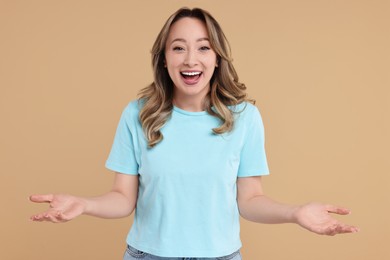 Photo of Portrait of happy surprised woman on beige background