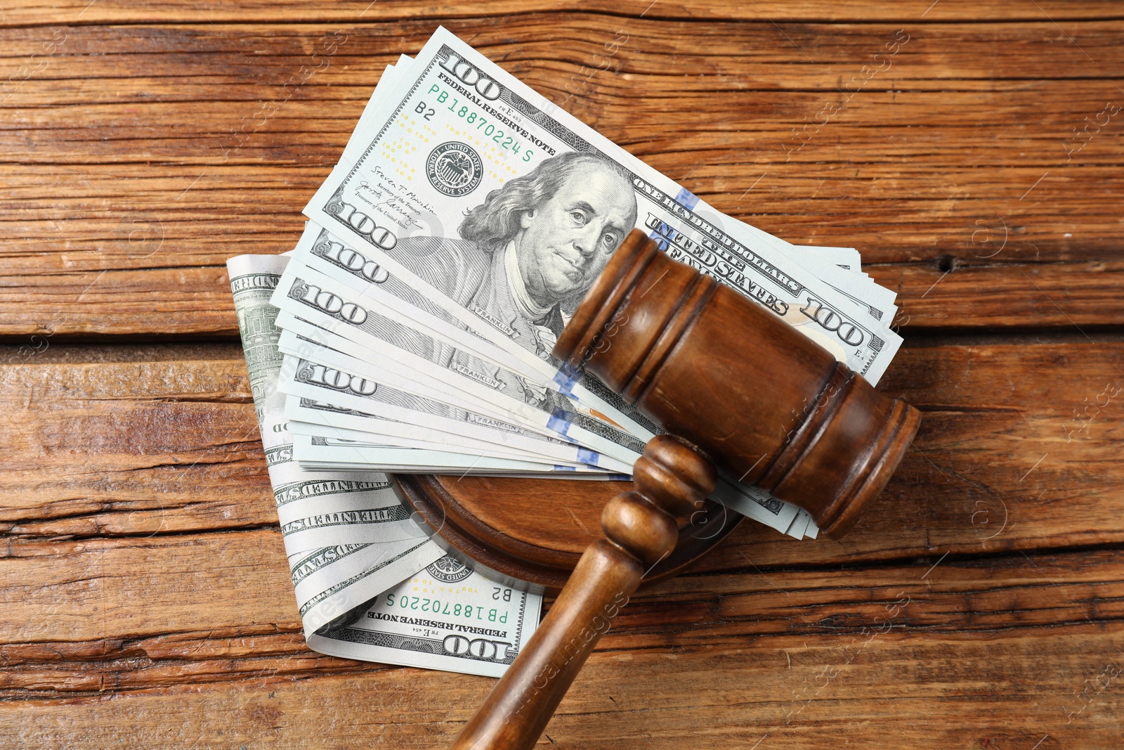 Photo of Judge's gavel and money on wooden table, top view