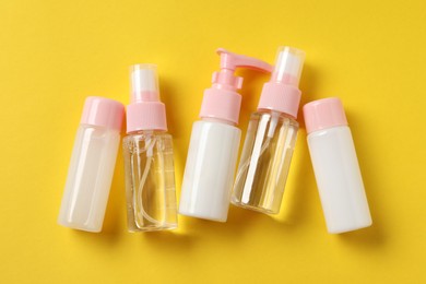 Photo of Cosmetic travel kit on yellow background, flat lay. Bath accessories