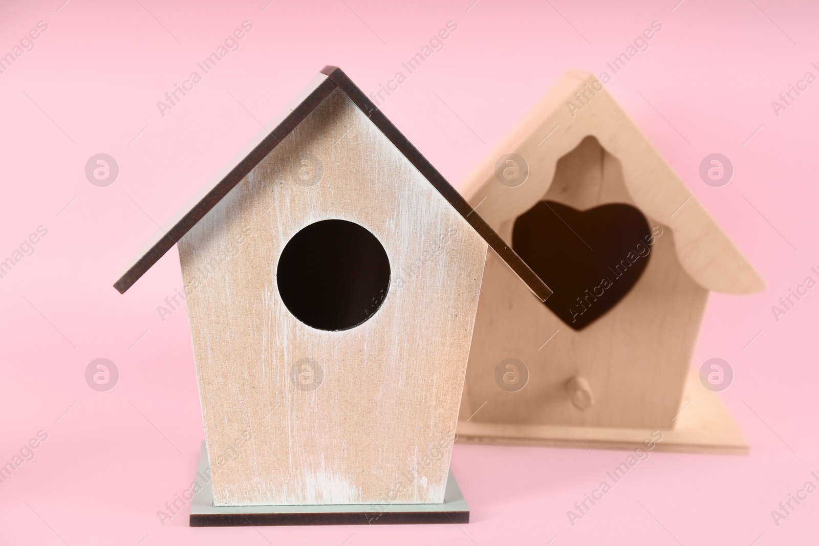 Photo of Beautiful wooden bird houses on pink background