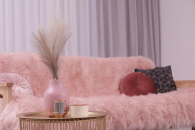 Photo of Vase and candles on coffee table near sofa in stylish room. Interior design