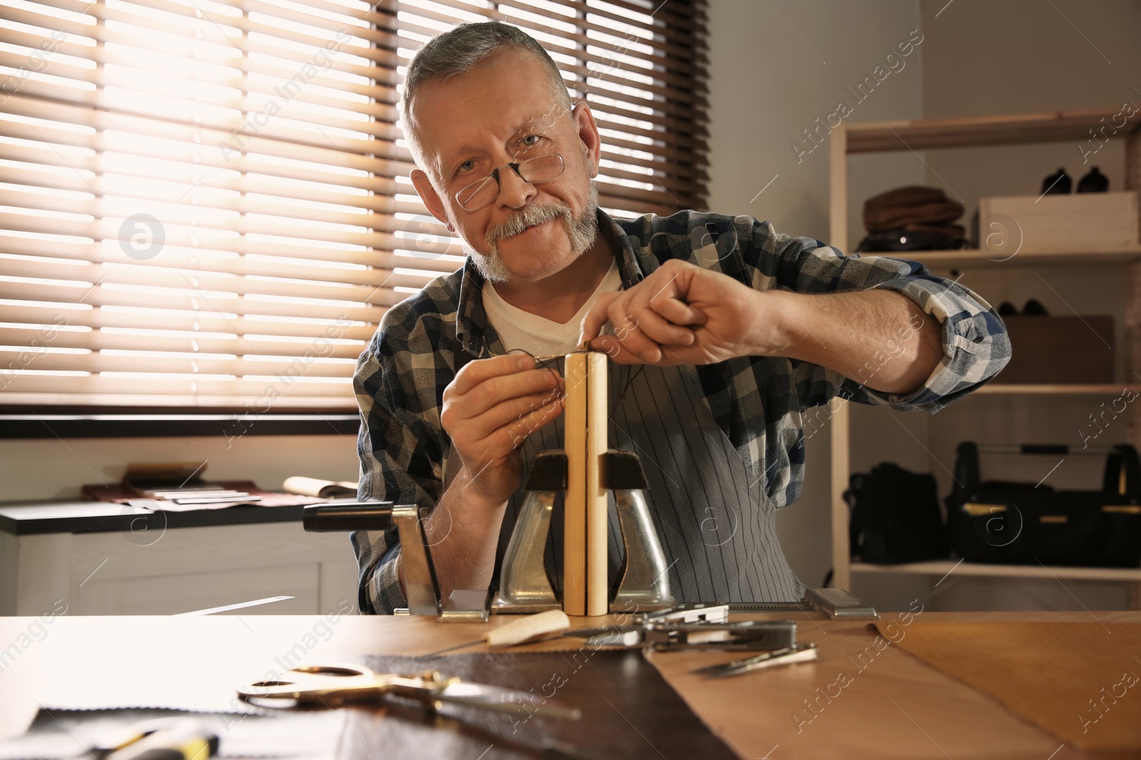 Photo of Man sewing piece of leather in workshop