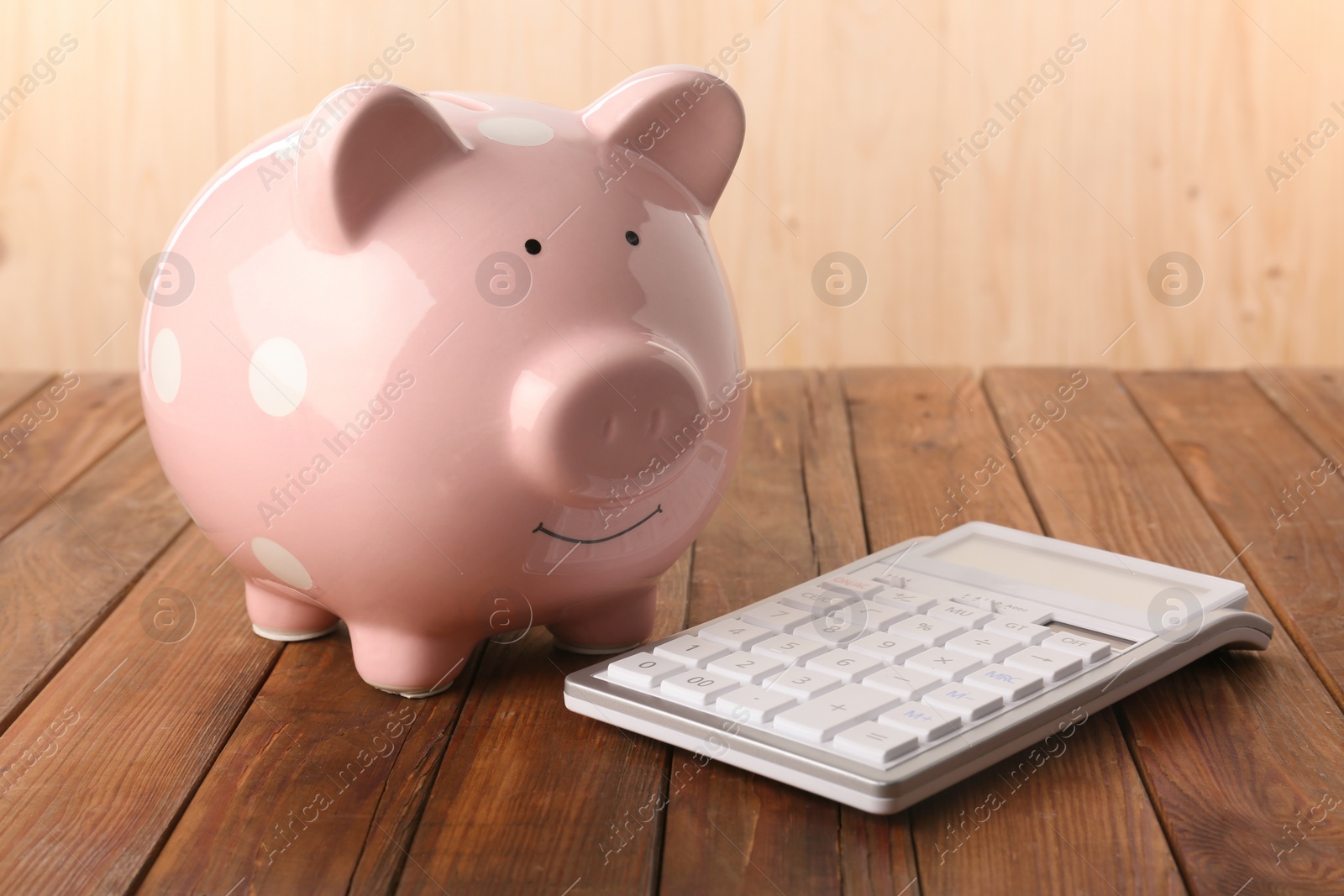 Photo of Calculator and piggy bank on wooden table