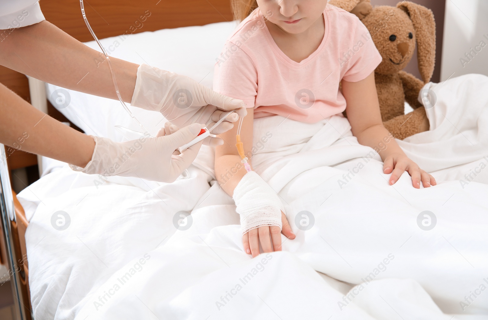 Photo of Doctor adjusting intravenous drip for little child in hospital