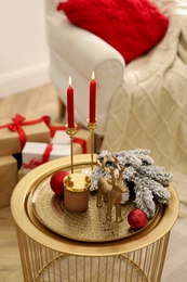 Photo of Christmas composition with decorative reindeer and candles on golden table in room