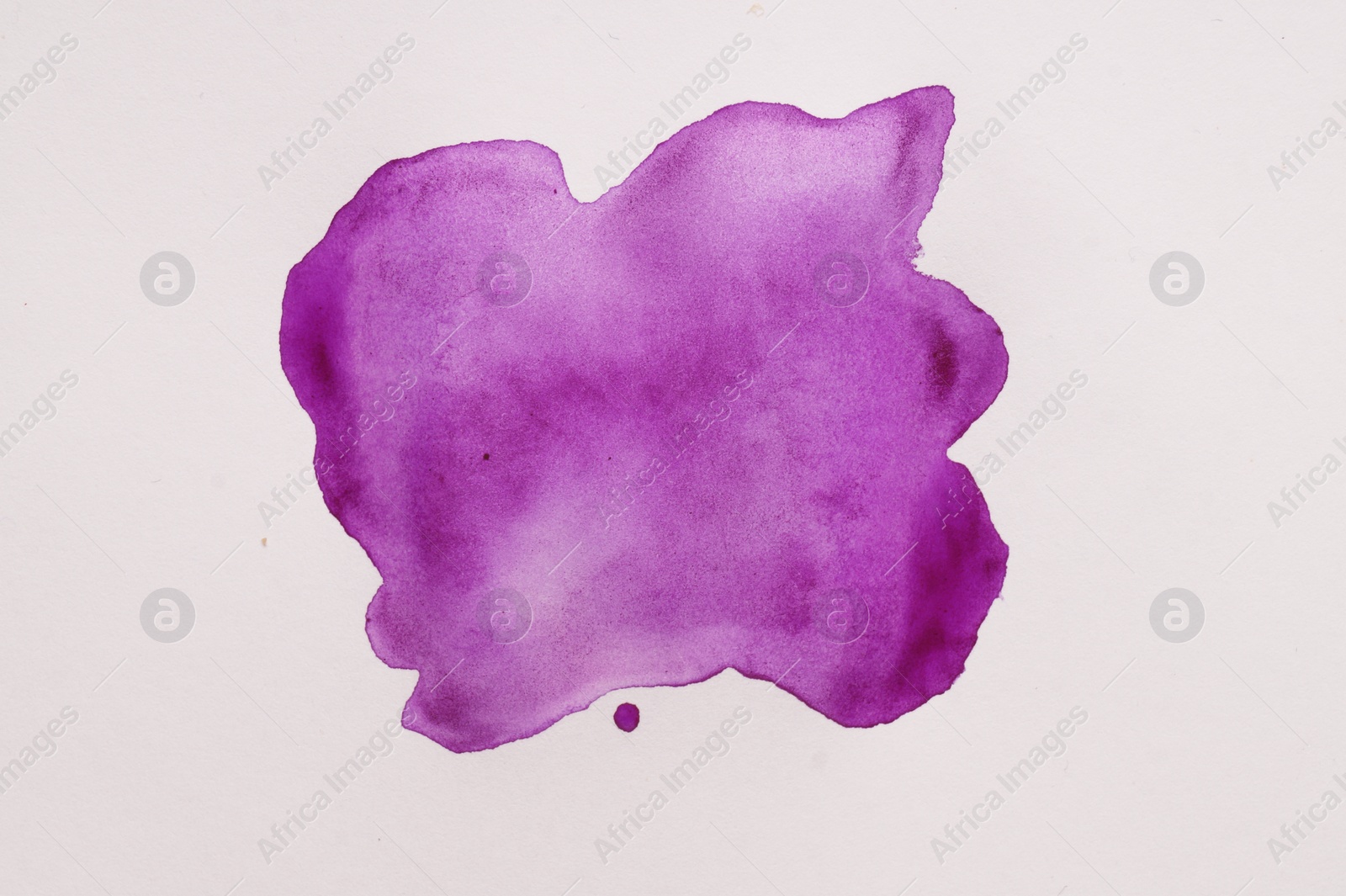 Photo of Blot of purple watercolor paint on white paper, top view