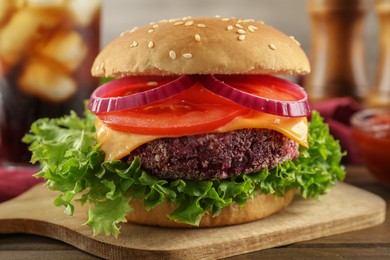 Photo of Tasty vegetarian burger with beet patty on wooden table, closeup