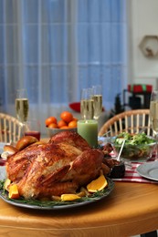 Photo of Festive dinner with delicious baked turkey and sparkling wine on table indoors, space for text. Christmas celebration
