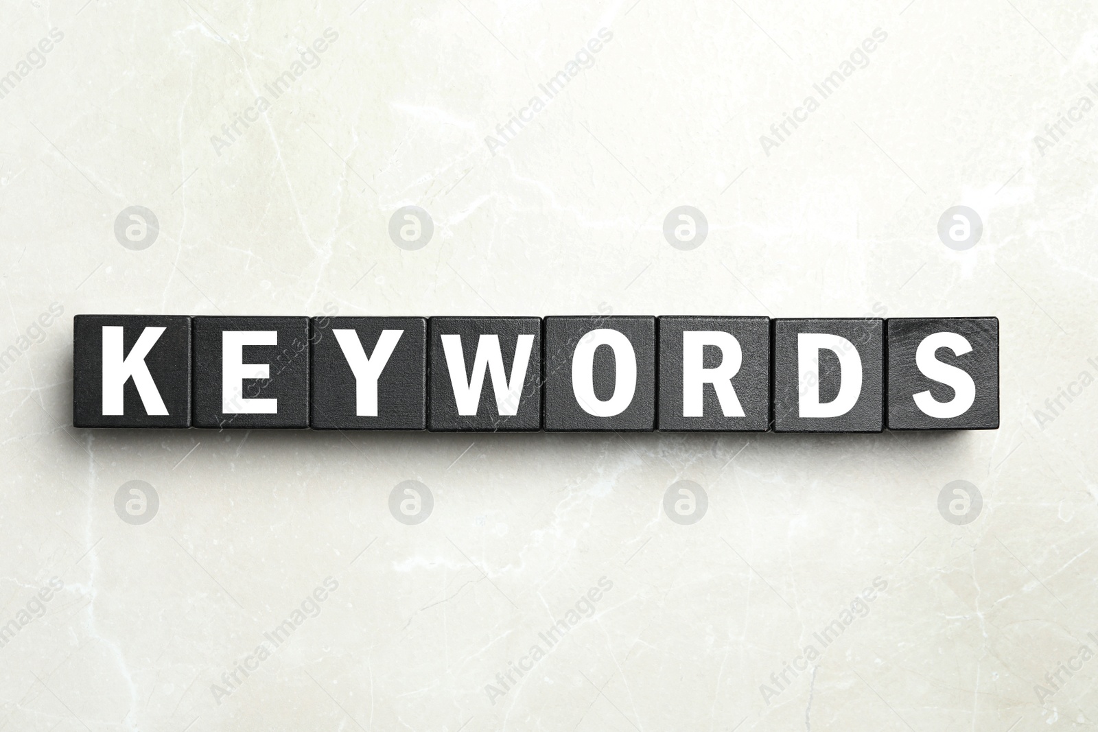 Photo of Word KEYWORDS made of black cubes on light background, flat lay
