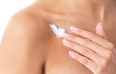 Photo of Young woman applying cream on light background, closeup. Beauty and body care