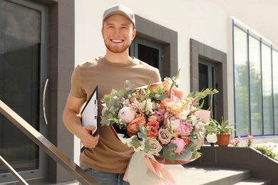 Happy delivery man with beautiful flower bouquet outdoors