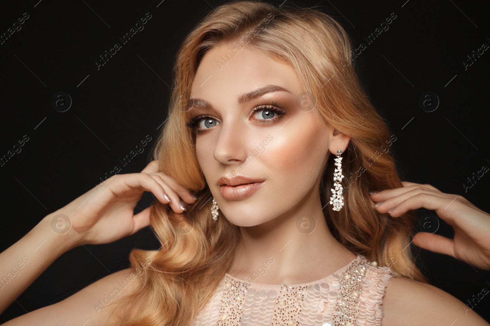 Photo of Beautiful young woman with elegant jewelry on dark background