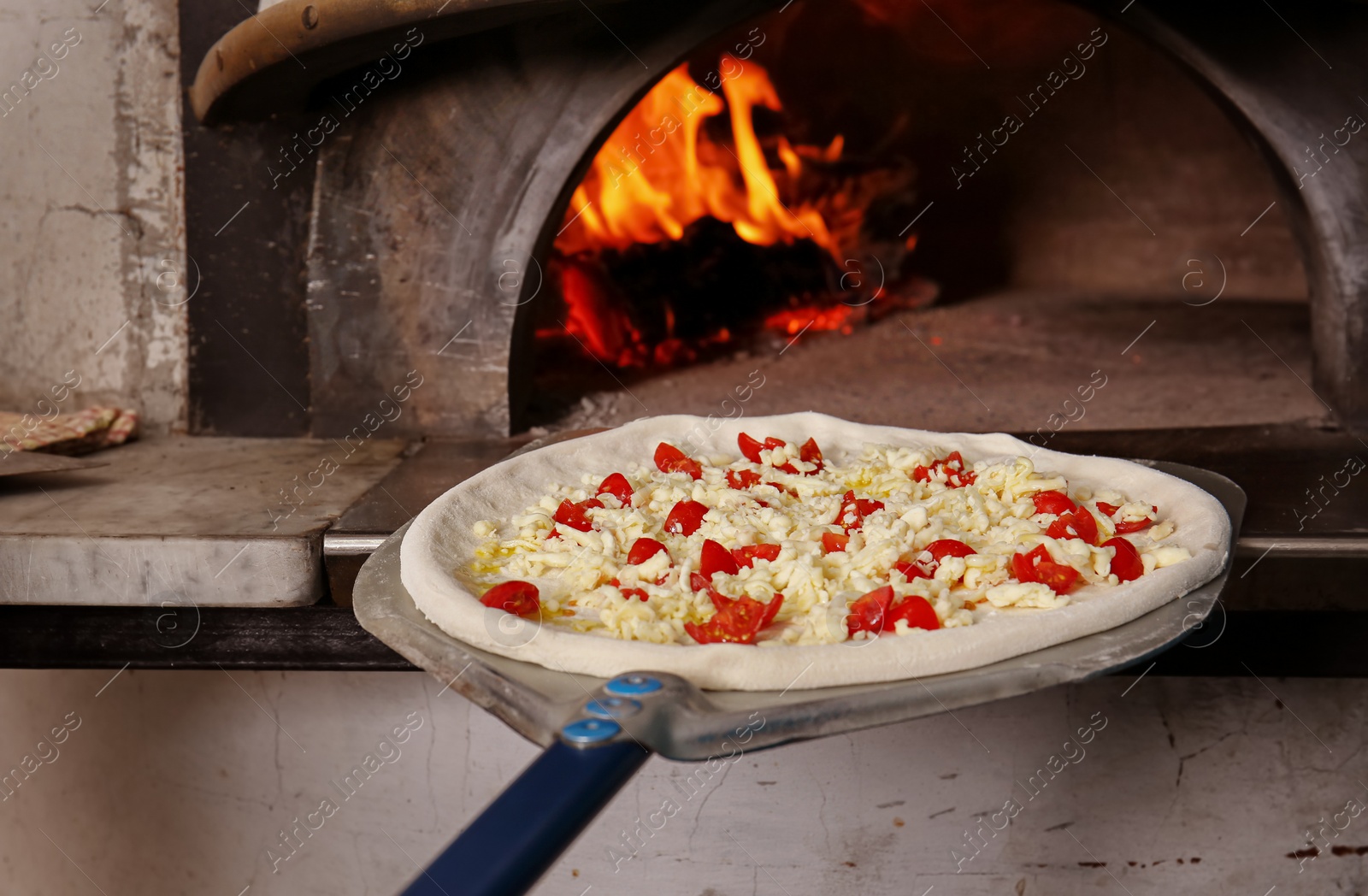 Photo of Putting tasty pizza into oven in  restaurant kitchen