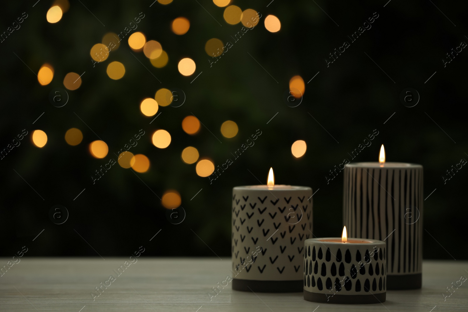 Photo of Burning candles on white wooden table outdoors, space for text. Bokeh effect