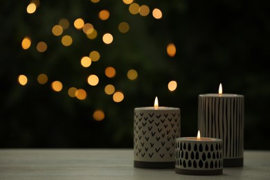 Photo of Burning candles on white wooden table outdoors, space for text. Bokeh effect
