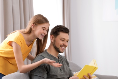 Photo of Father and his teenager daughter with book at home