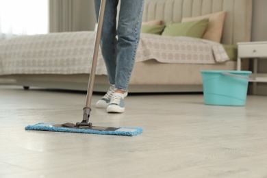 Photo of Woman cleaning floor with mop at home, closeup