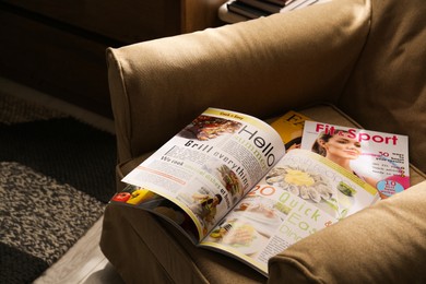 Photo of Different lifestyle magazines on comfortable armchair indoors