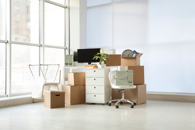 Photo of Cardboard boxes and packed belongings in office. Moving day