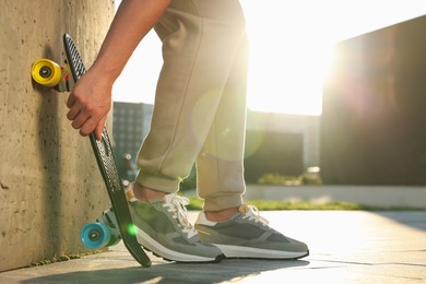 Man with skateboard wearing stylish sneakers outdoors, closeup