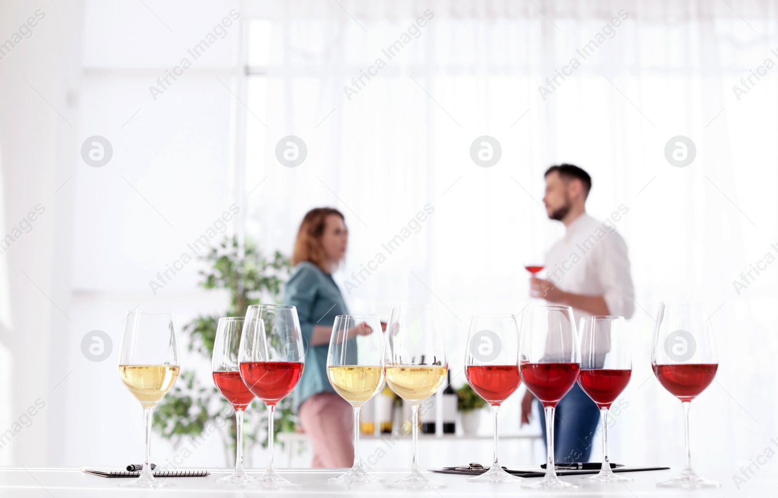 Photo of Glasses with delicious wine and blurred people on background