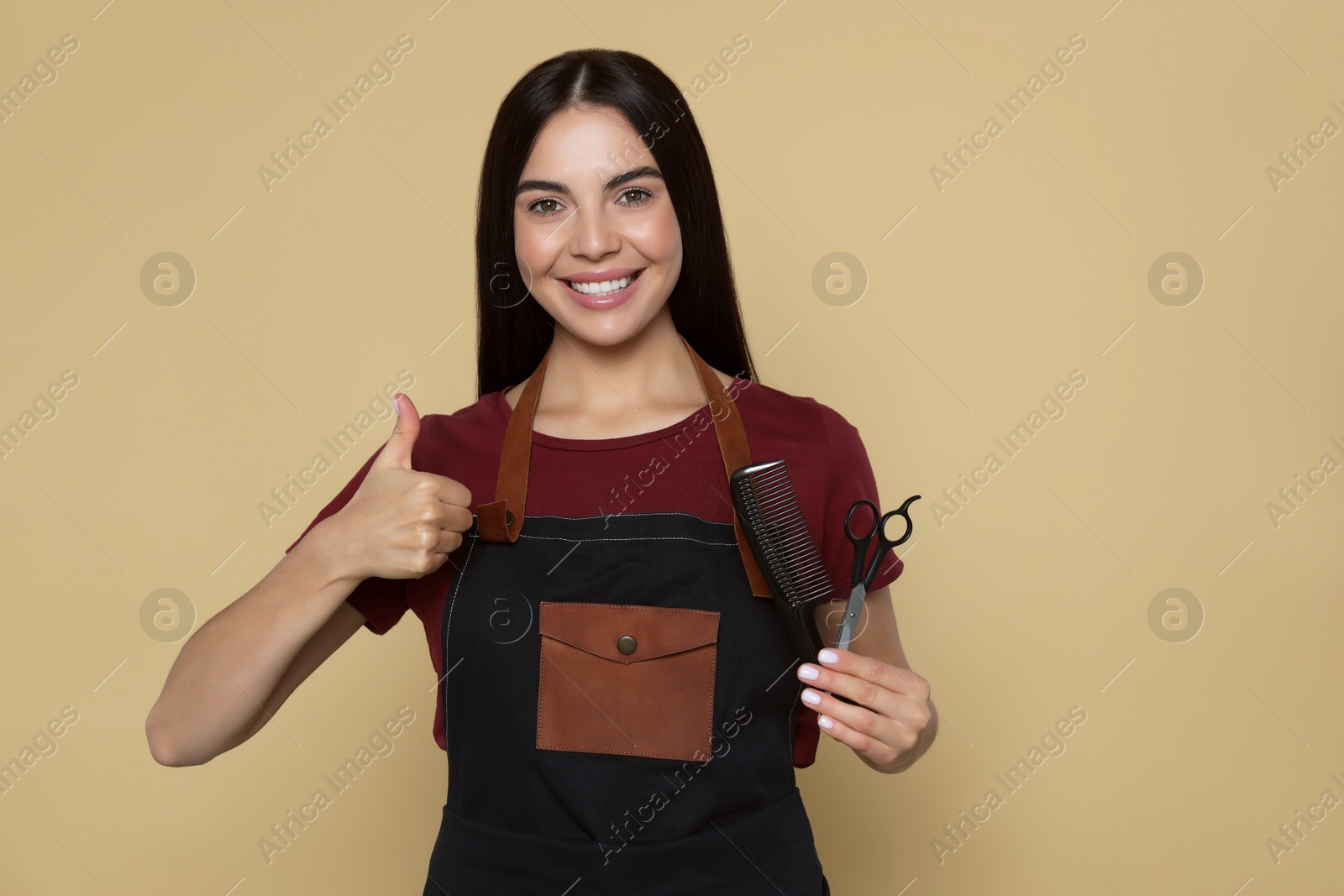 Photo of Portrait of happy hairdresser with professional scissors and comb on beige background, space for text