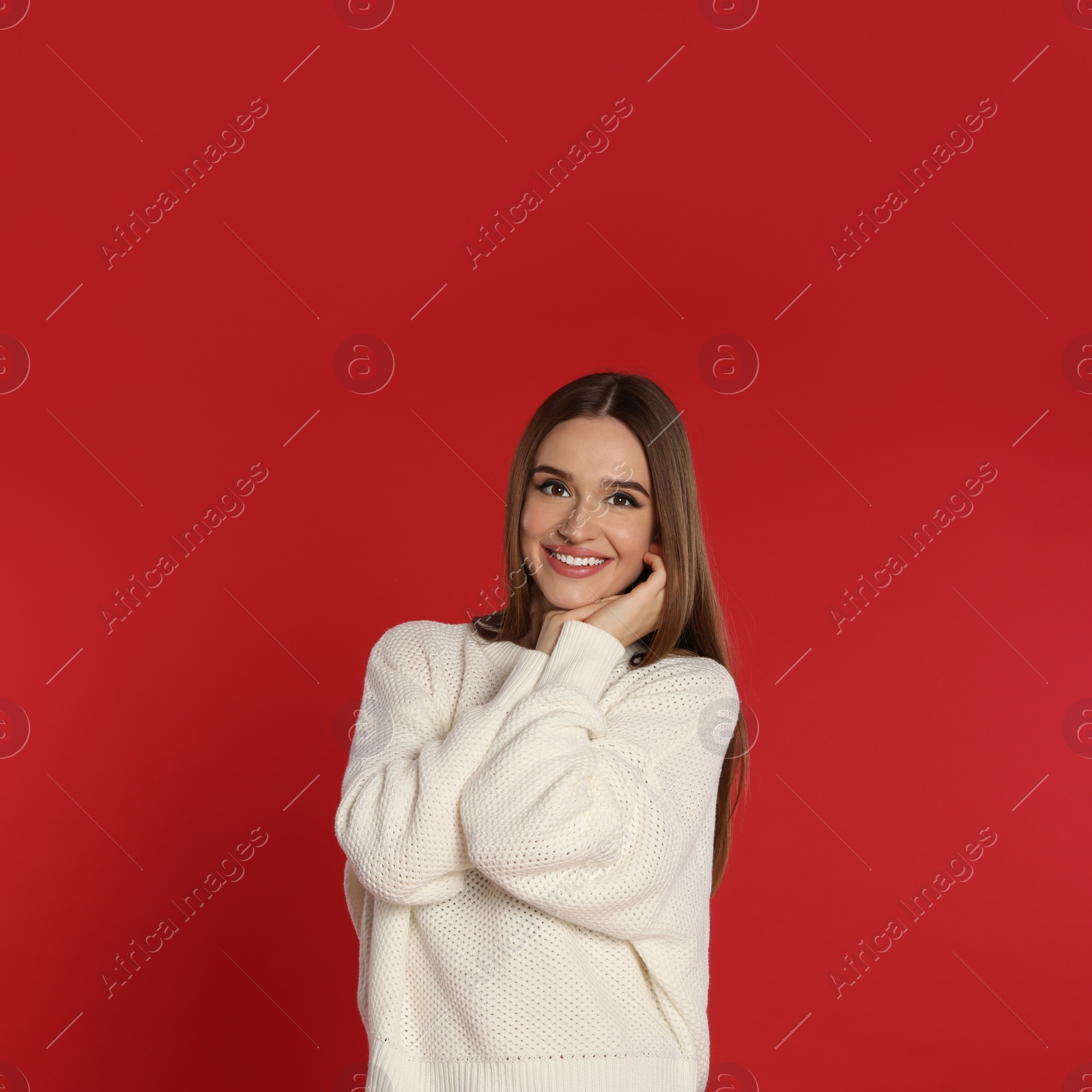 Photo of Beautiful young woman in white sweater on red background. Winter season