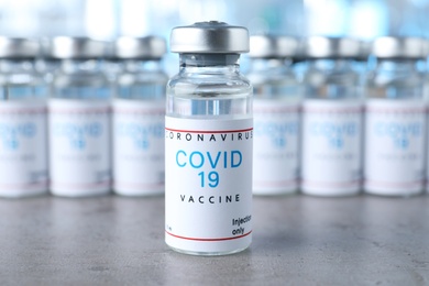 Glass vial with COVID-19 vaccine on grey table