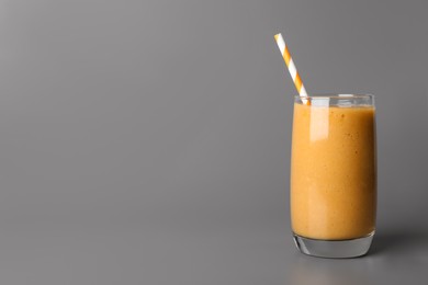 Photo of Glass with delicious fruit smoothie on grey background. Space for text