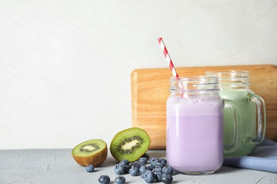 Mason jars with delicious milk shakes and ingredients on table. Space for text