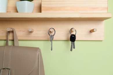 Photo of Wooden hanger for keys on light green wall