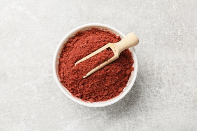 Photo of Cranberry powder in bowl and scoop on light grey table, top view