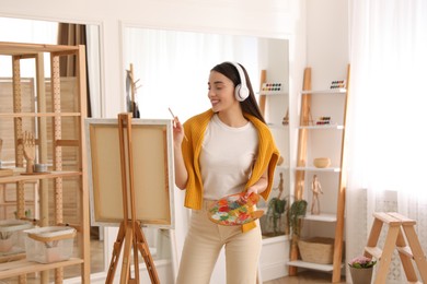 Photo of Beautiful young woman listening to music while drawing at home