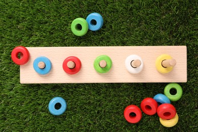 Photo of Stacking and counting game wooden pieces on artificial grass, flat lay. Educational toy for motor skills development