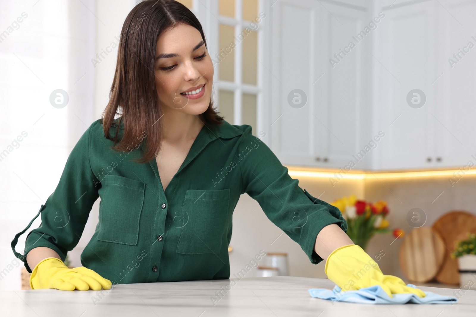 Photo of Woman cleaning table with rag in kitchen