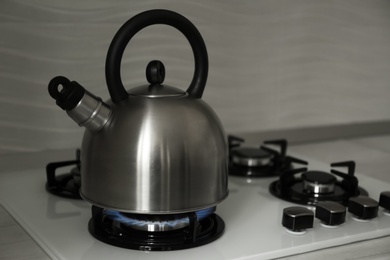 Photo of Steel kettle with whistle on modern gas stove. Space for text