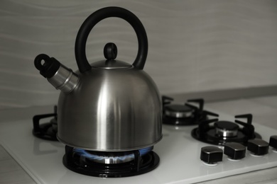 Steel kettle with whistle on modern gas stove. Space for text